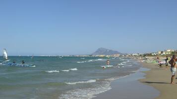 Guests can enjoy a beach day with calm waters and scenic views of the surrounding mountains and coastal town.