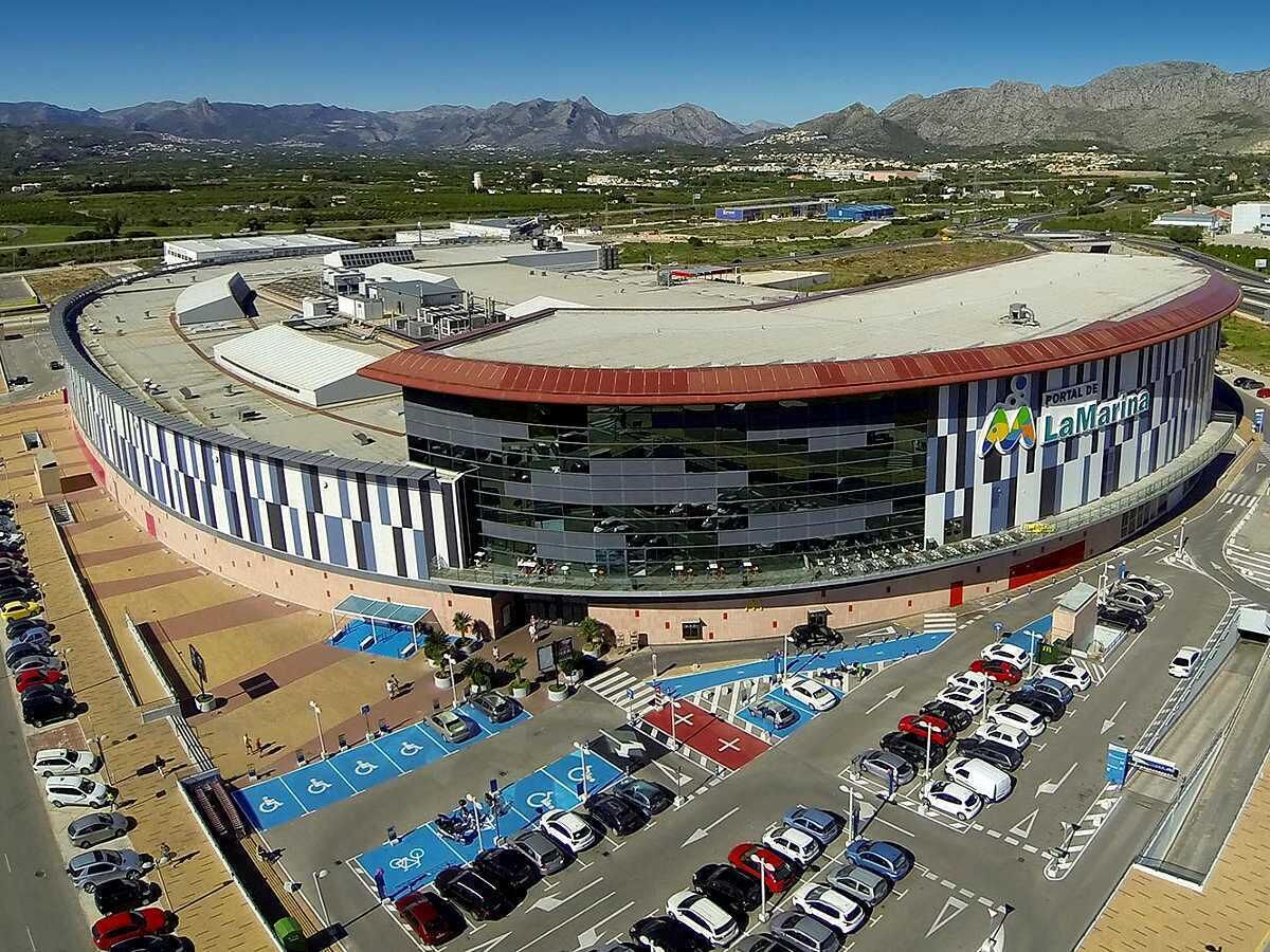 A large, circular building with a curved roof, surrounded by a parking lot with blue handicap parking spaces.