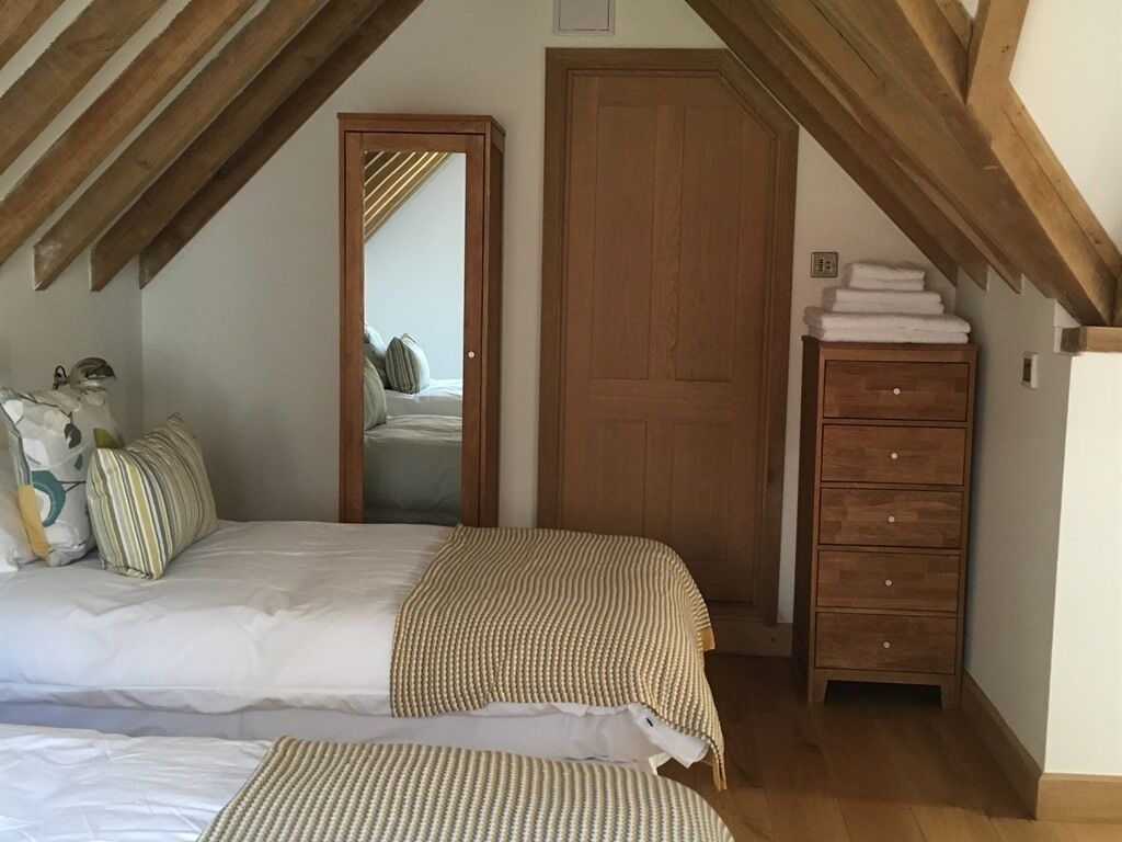 Ein Schlafzimmer mit zwei Betten, einem Holzschrank und einem Spiegel.