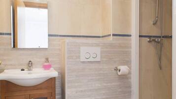 A bathroom with a sink, mirror, toilet, and shower.