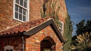 A traditional brick house with a tiled roof, a stone archway entrance, and a garden with large boulders and plants. - The Leagate Inn (Boston)