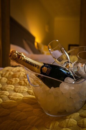 A bottle of Lanson champagne in a glass container with ice cubes, surrounded by empty champagne glasses on a table.