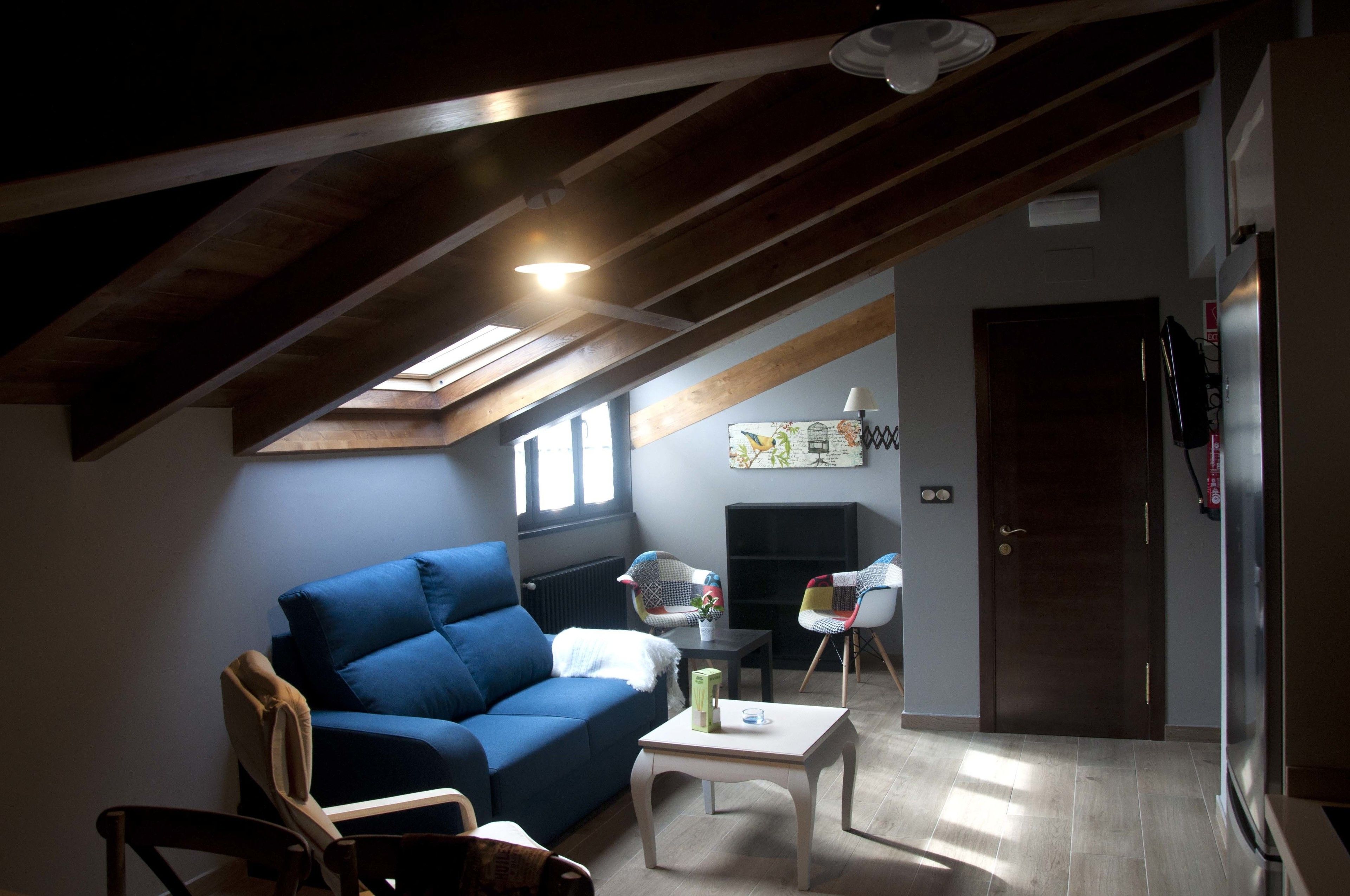 A living room with a blue sofa, a small table, and a chair. There is a door and a radiator in the background.