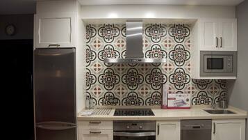 Una cocina con refrigerador de acero inoxidable, microondas, horno y un salpicadero decorativo.