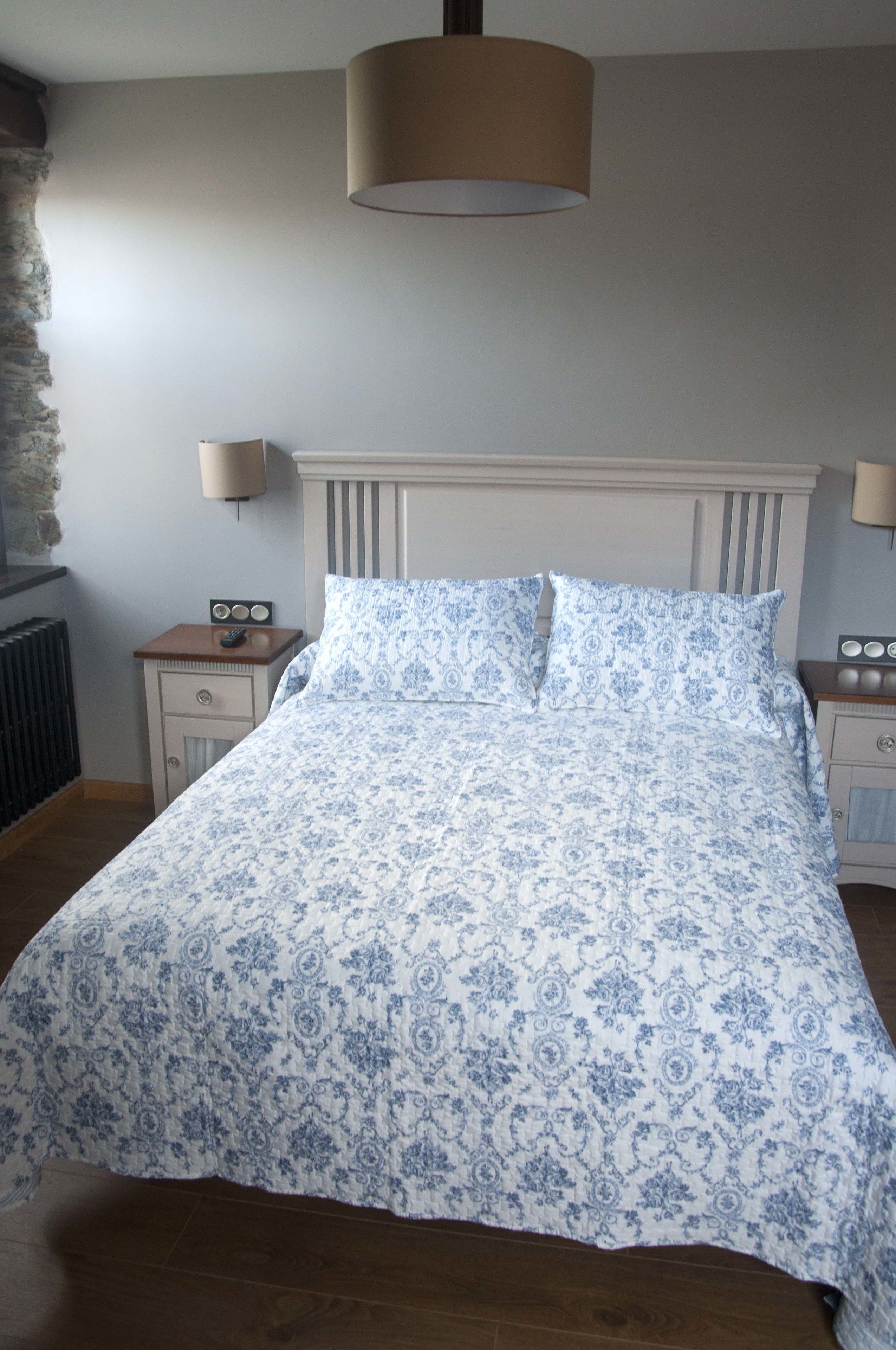 Une chambre à coucher avec un lit, deux tables de chevet, une lampe et un radiateur.