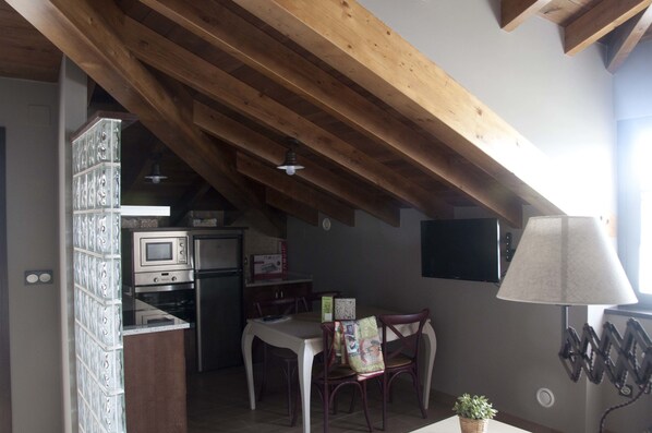 A kitchen with a microwave, oven, and refrigerator. There is a dining table with chairs and a lamp. - Casa Pacho Apartamentos Rurales (Valdes)
