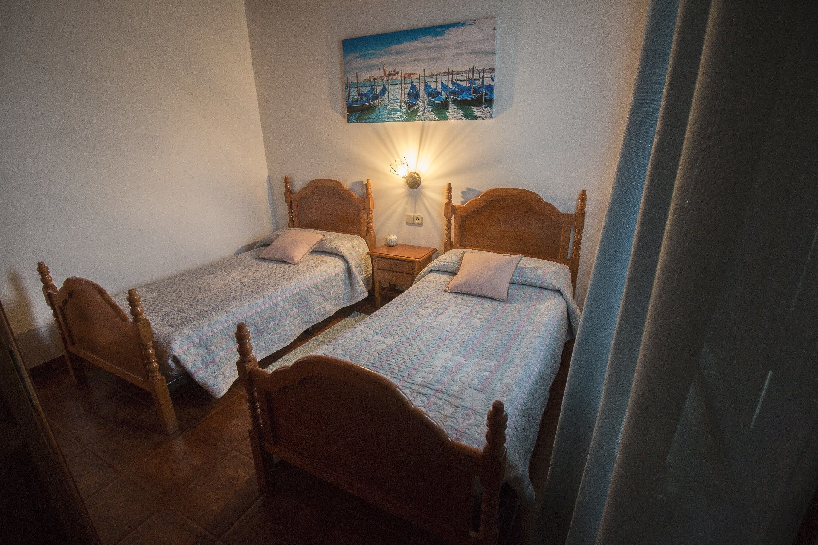 Ein Zimmer mit zwei Holzbett, einem Nachttisch und einer Wandlampe.