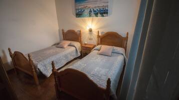 Ein Zimmer mit zwei Holzbett, einem Nachttisch und einer Wandlampe.