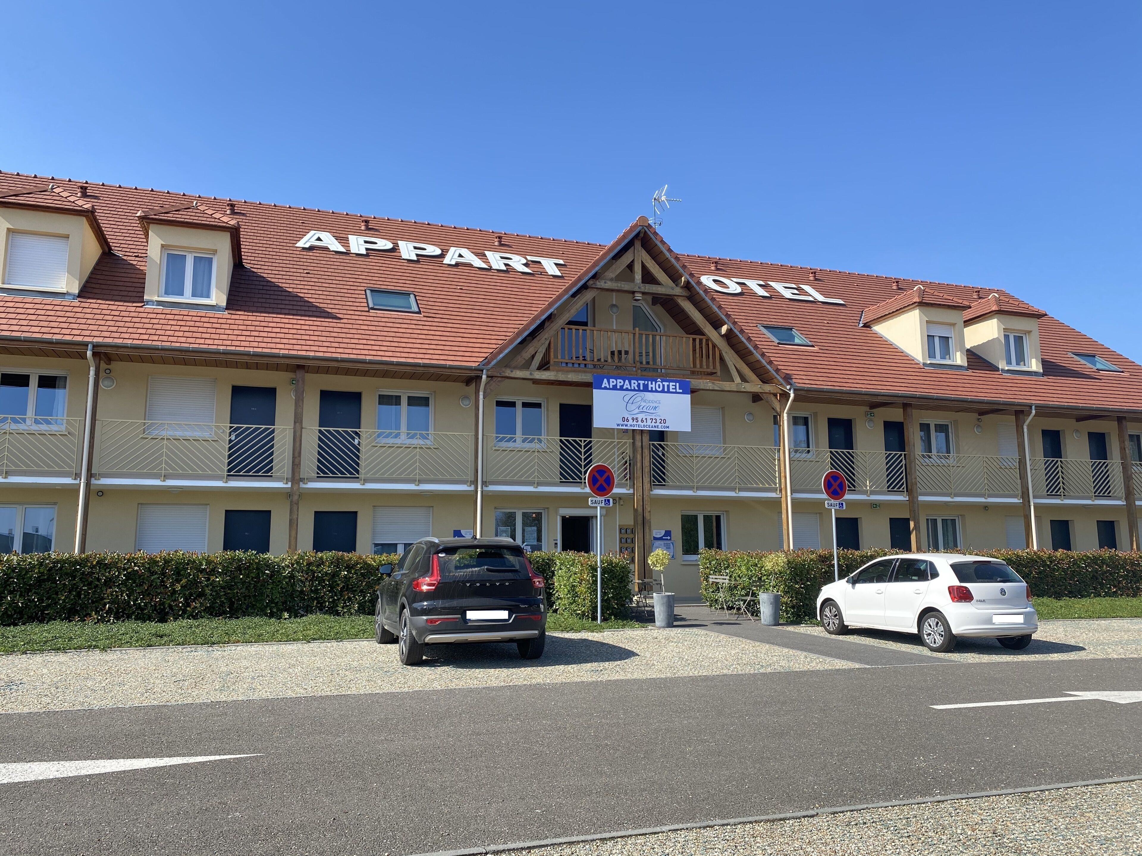 Ein Hotel namens "Appart Hôtel" mit rotem Ziegeldach, mehreren Balkonen und einer Beschilderung, die "Appart" und "Hôtel" auf Französisch ausweist.