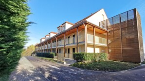 A modern hotel with multiple balconies, a covered walkway, and a well-maintained garden.