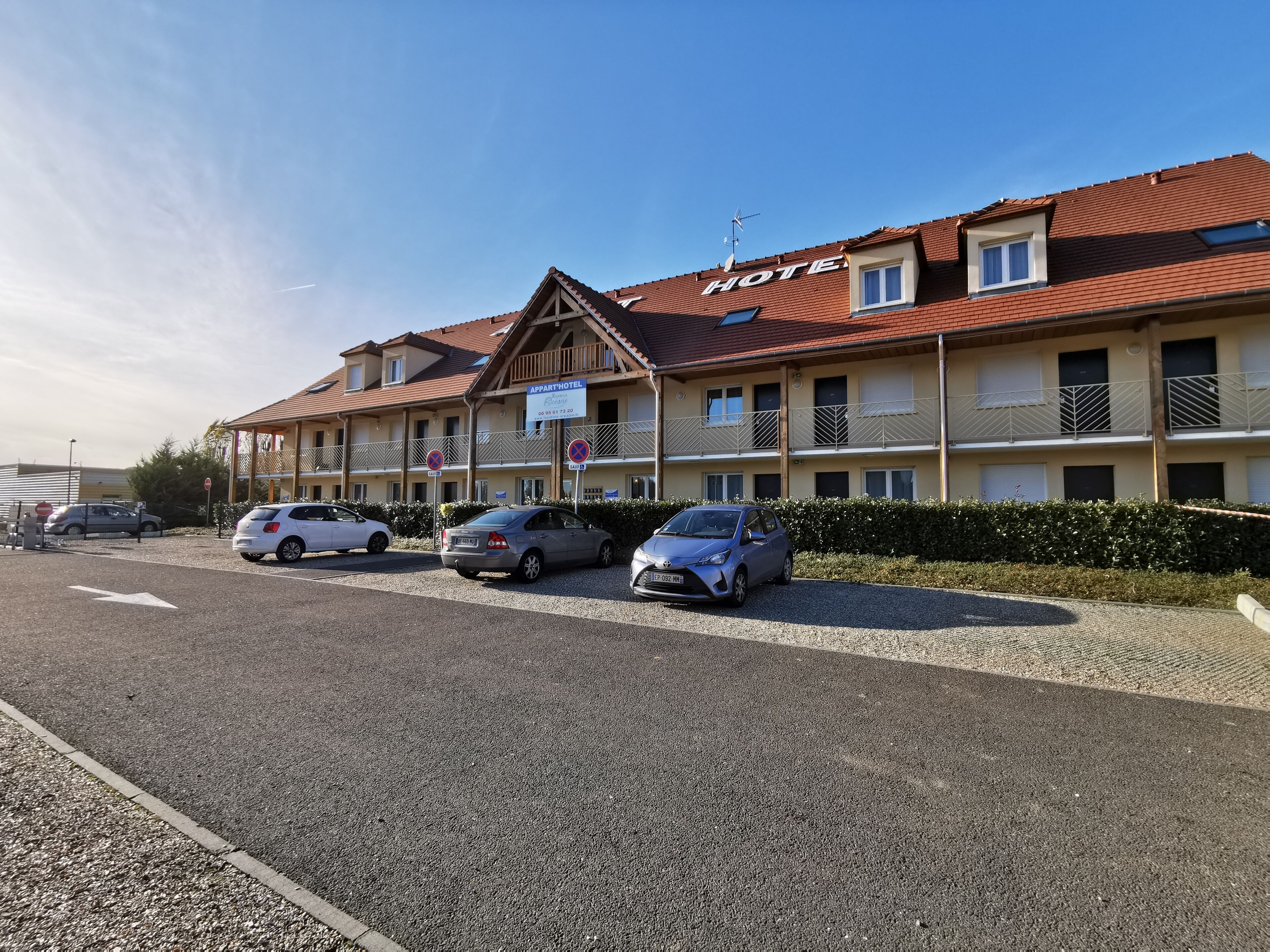 A hotel with a red-tiled roof, multiple balconies, and a sign indicating it is an apartment hotel.