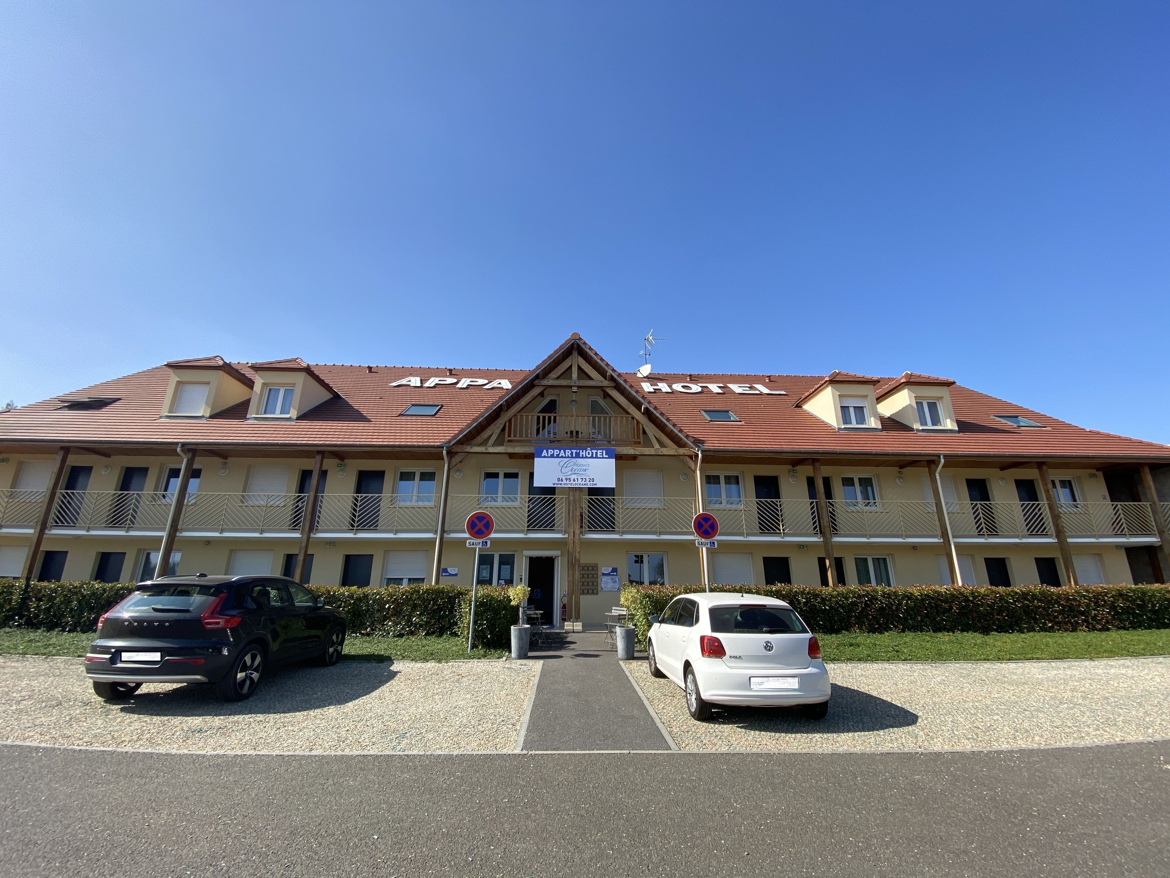 A hotel with a red-tiled roof, balconies, and a sign indicating it is an apartment hotel.