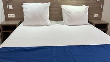 A hotel room with a large bed, two bedside tables, and a wooden headboard.