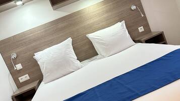 Habitació d'hotel amb un llit, dues taules de nit, un capçal de llit i una estantanya penjada a la paret.