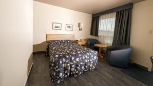 Una habitación de hotel con cama, escritorio, silla y una mesita.