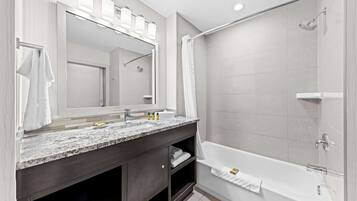 Un baño moderno con un espejo grande, dos lavamanos, una bañera y una ducha.