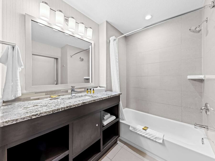 Un baño moderno con un espejo grande, dos lavamanos, una bañera y una ducha.