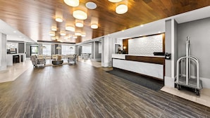 Un hall d’entrée spacieux avec un plafond en bois, un comptoir d’accueil, un espace salon et une cheminée.