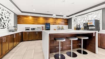 A modern kitchen with a central island, bar stools, and a coffee machine.