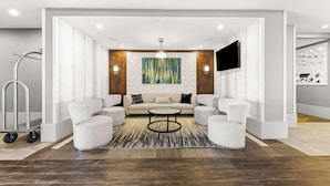 Un salon moderne avec un ensemble de canapés, une table basse et un grand tableau abstrait accroché au mur.