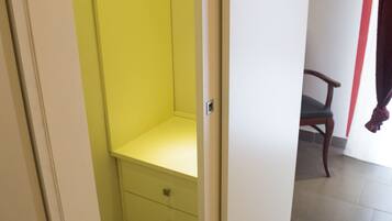 A narrow hallway with a yellow closet, a wooden chair, and a red curtain.