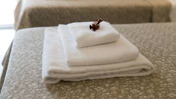 Una toalla blanca doblada cuidadosamente sobre una cama con edredón estampado con motivos florales.
