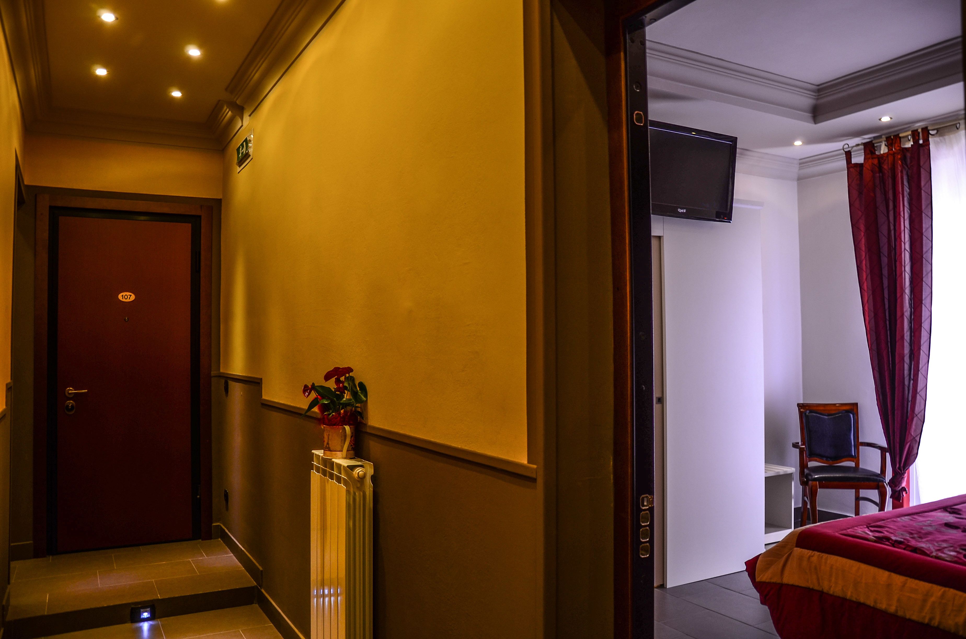 Ein Hotelzimmer mit einem Bett, einem an der Wand montierten Fernseher, einem Heizkörper und einer Tür mit einer Nummer.
