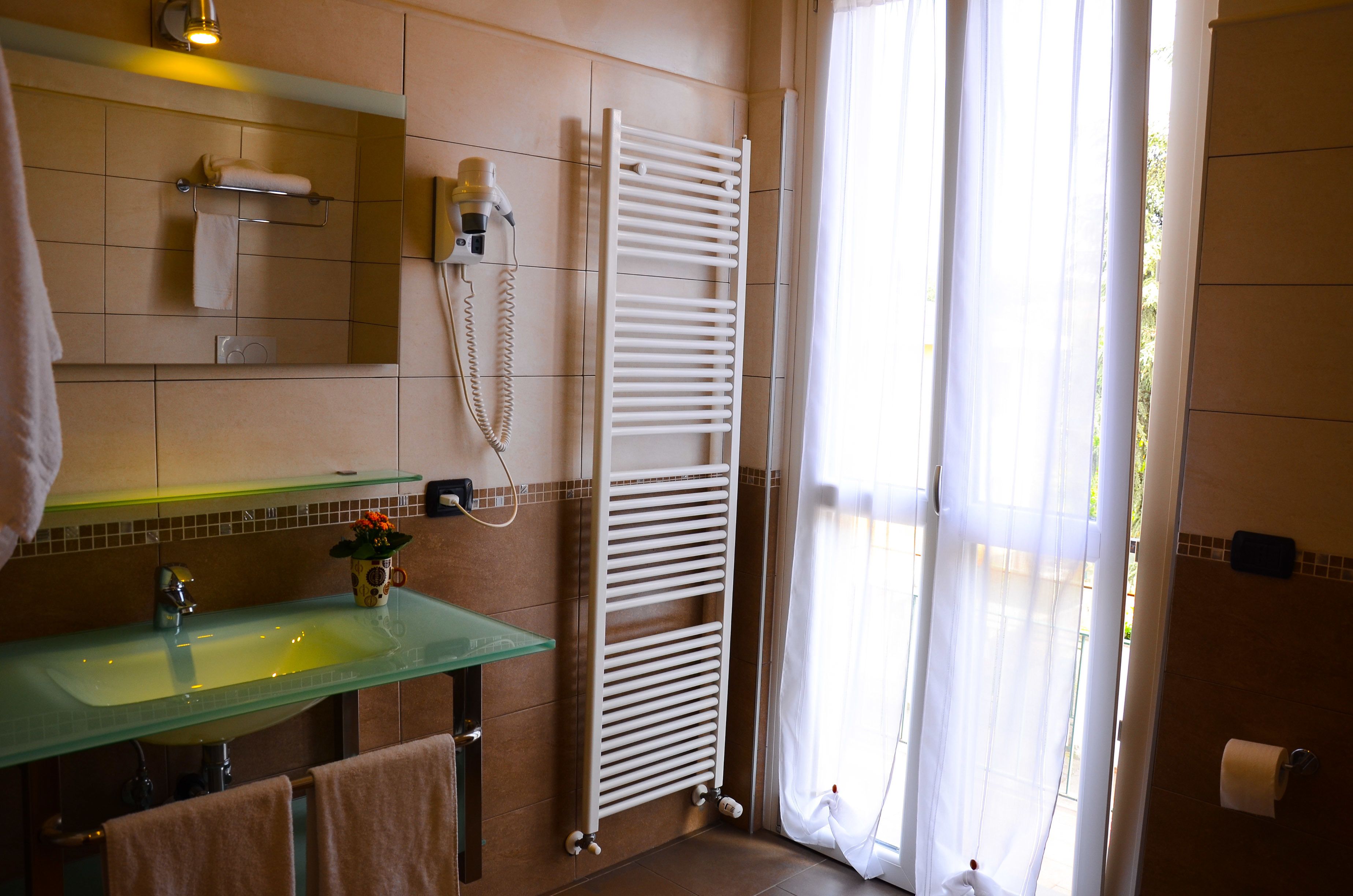 Une salle de bain avec un lavabo en verre, un porte-serviettes et une serviette blanche suspendue.