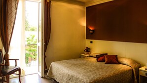 Een hotelkamer met een bed, nachtkastje, stoel en uitzicht op de natuur via een schuifdeur.
