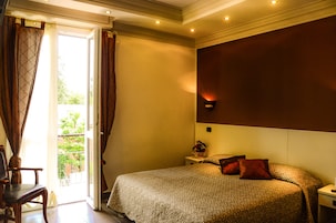 Habitación de hotel con una cama, una mesita de noche, una silla y vistas al exterior a través de una puerta corrediza.