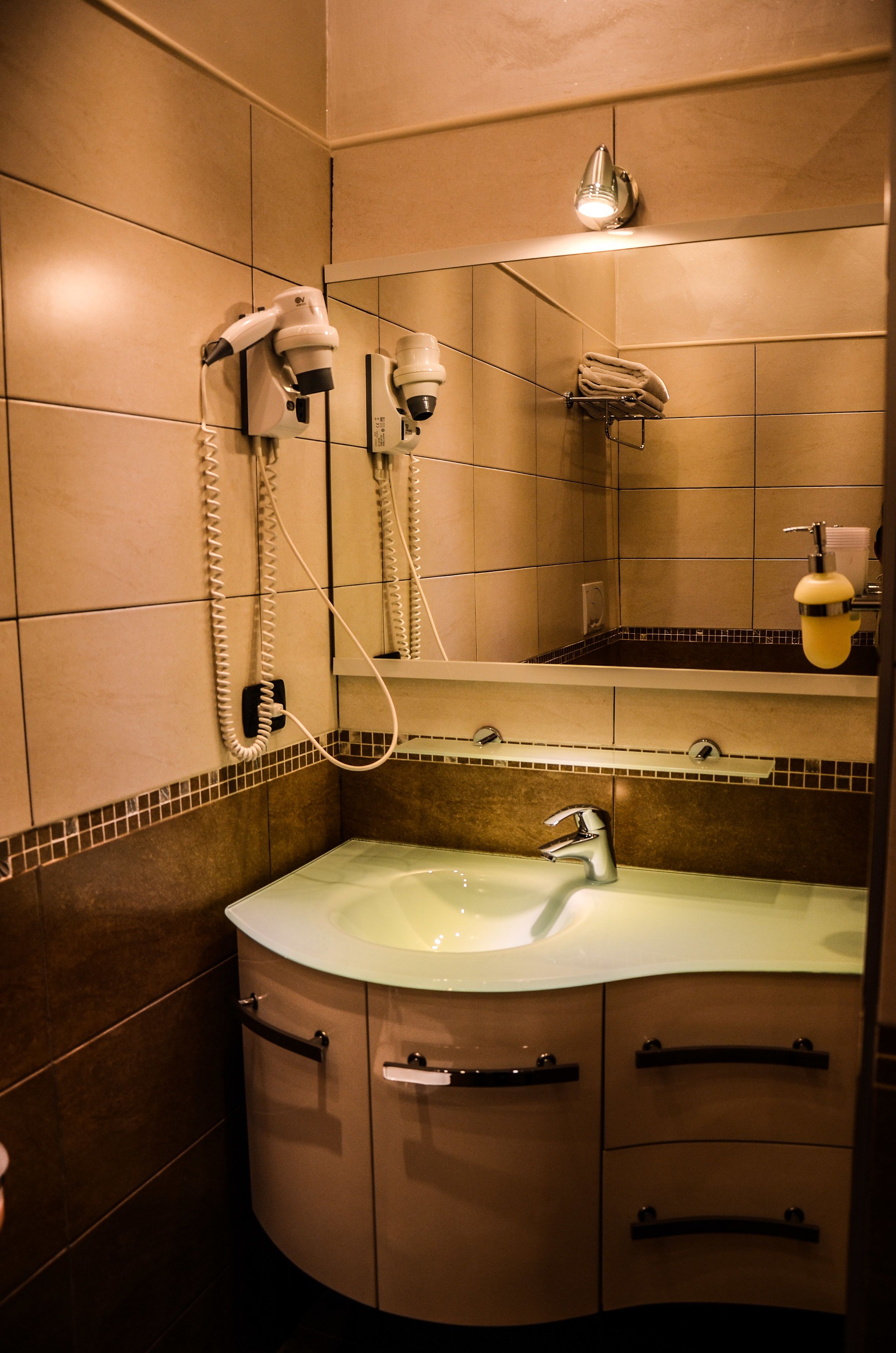 Un baño con lavamanos, espejo, toallero y secador de pelo.