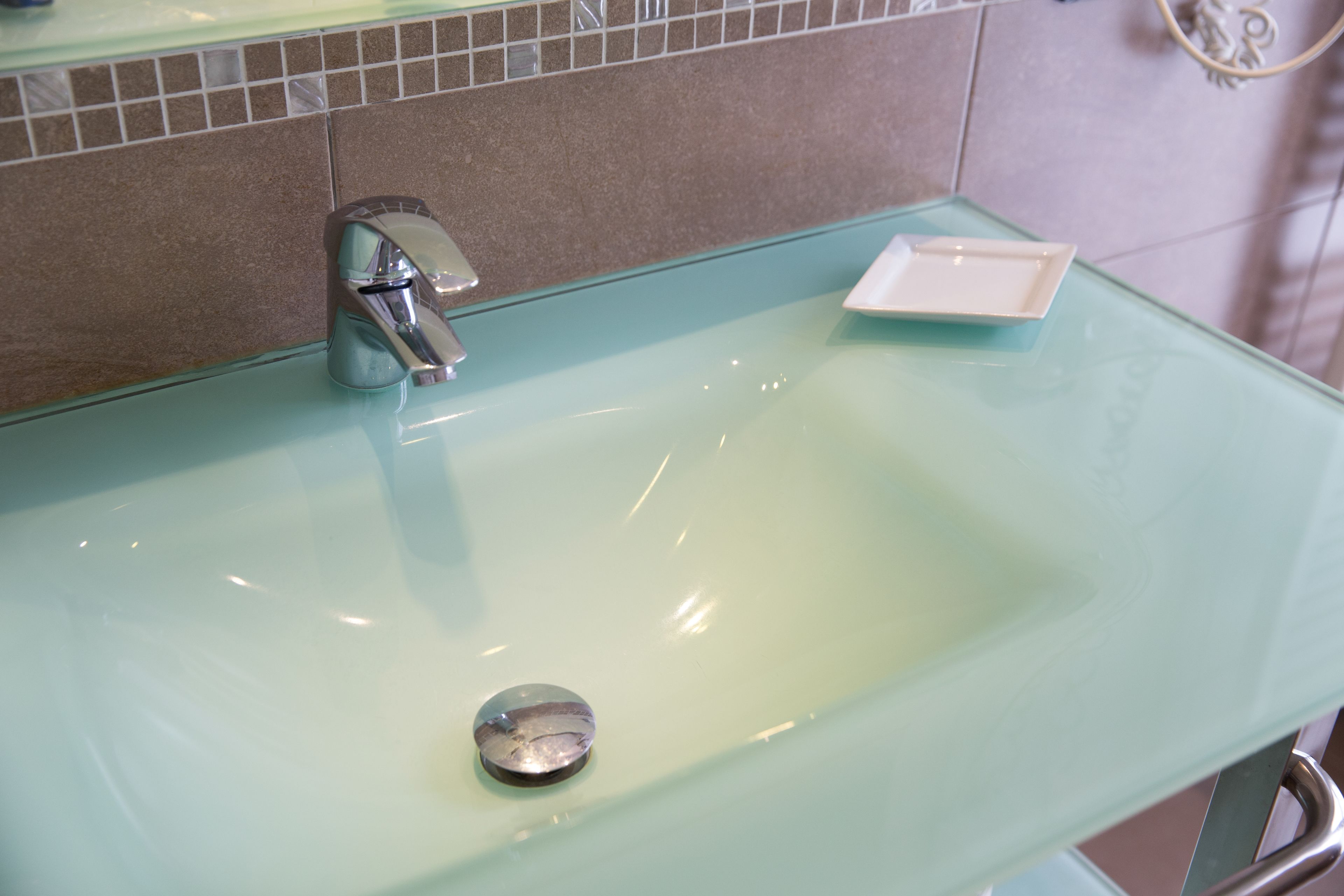 A bathroom sink with a chrome faucet and a small white soap dish.