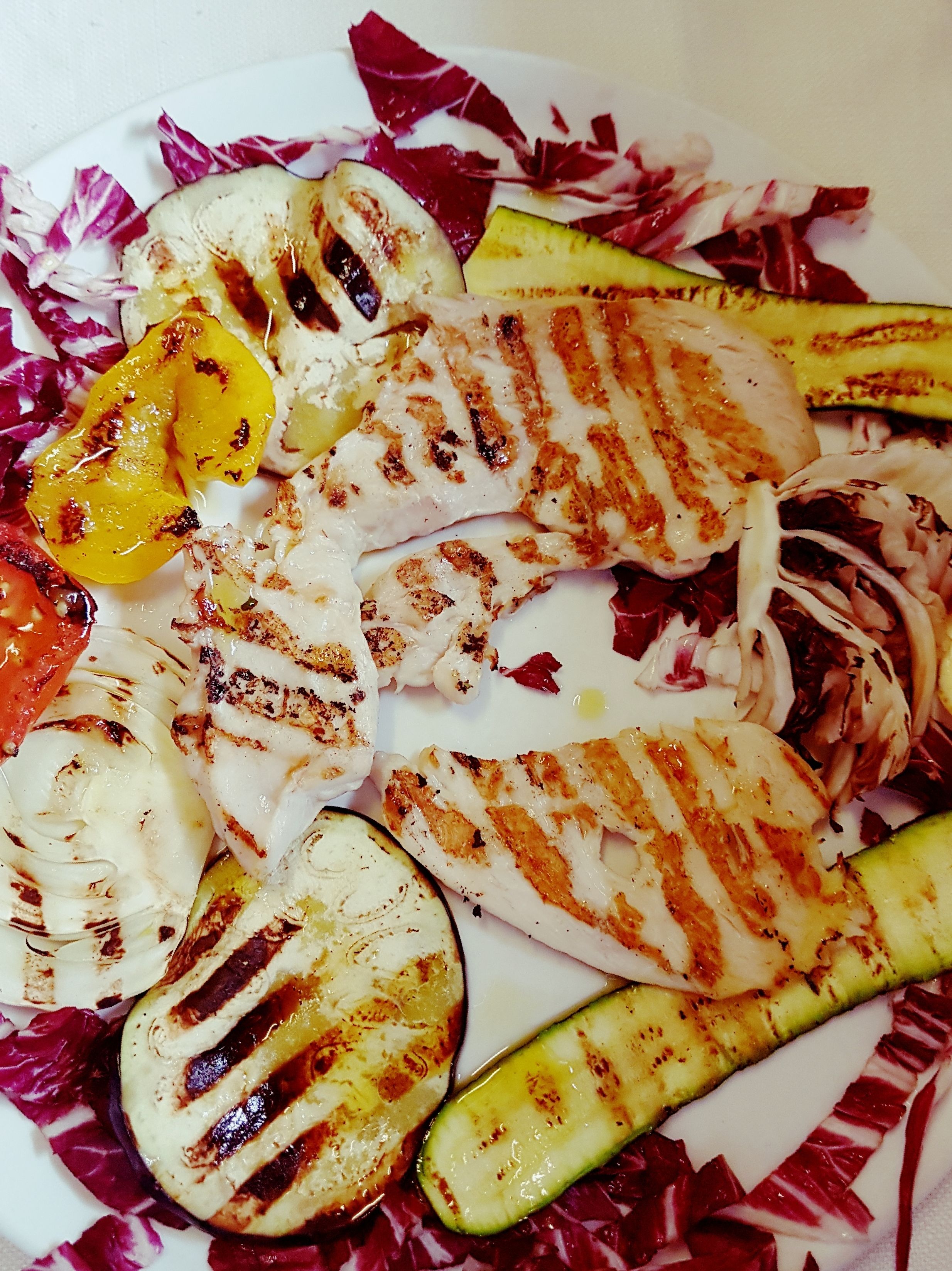 A plate of grilled vegetables and chicken.