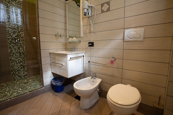 Un baño con bidé, inodoro y lavamanos.