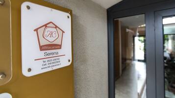 Une plaque portant le nom «
Serena
» et des coordonnées, fixée à un mur dont la surface est texturée.