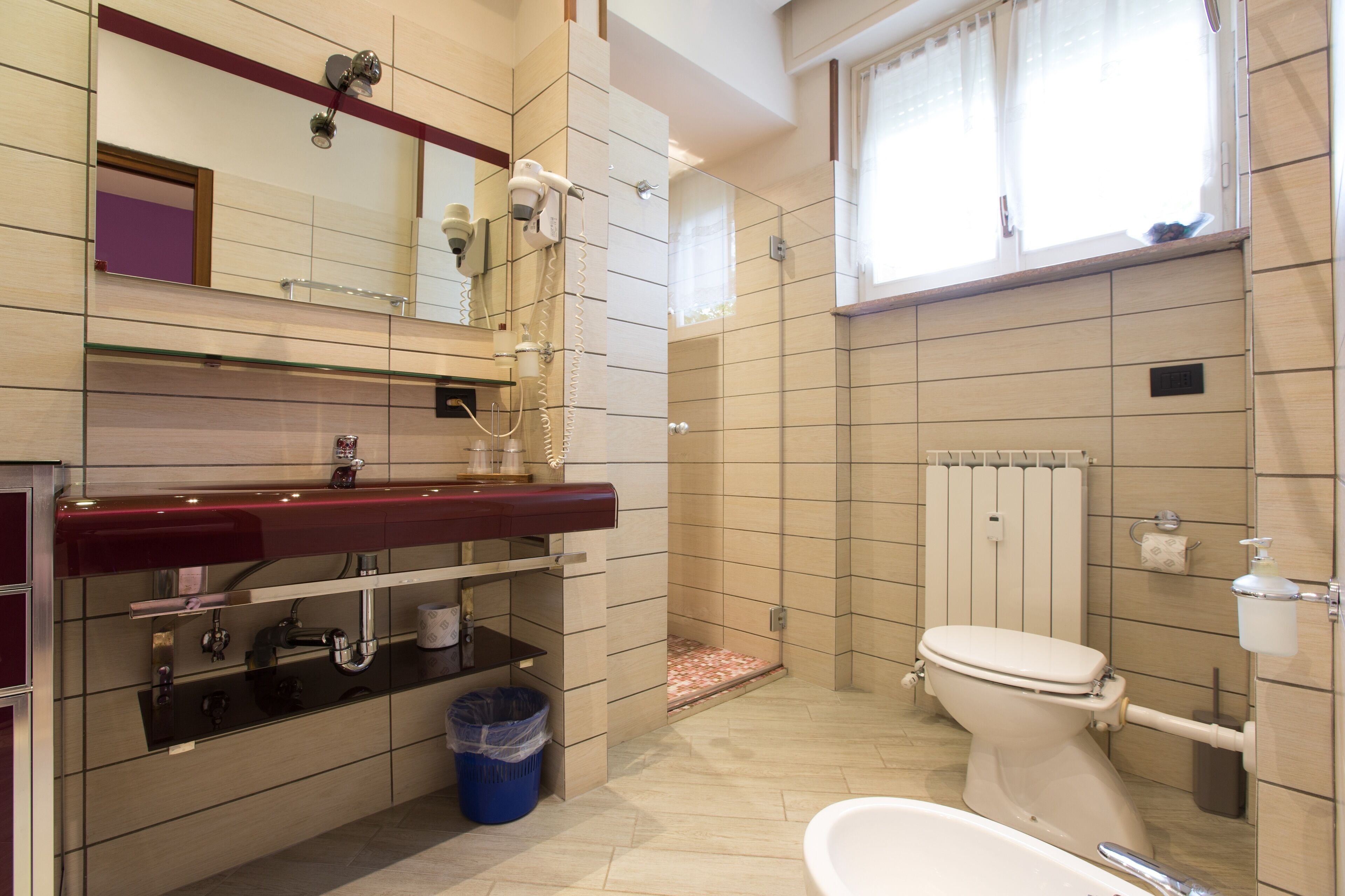 Et badeværelse med toilet, håndvask, spejl og bruser.
