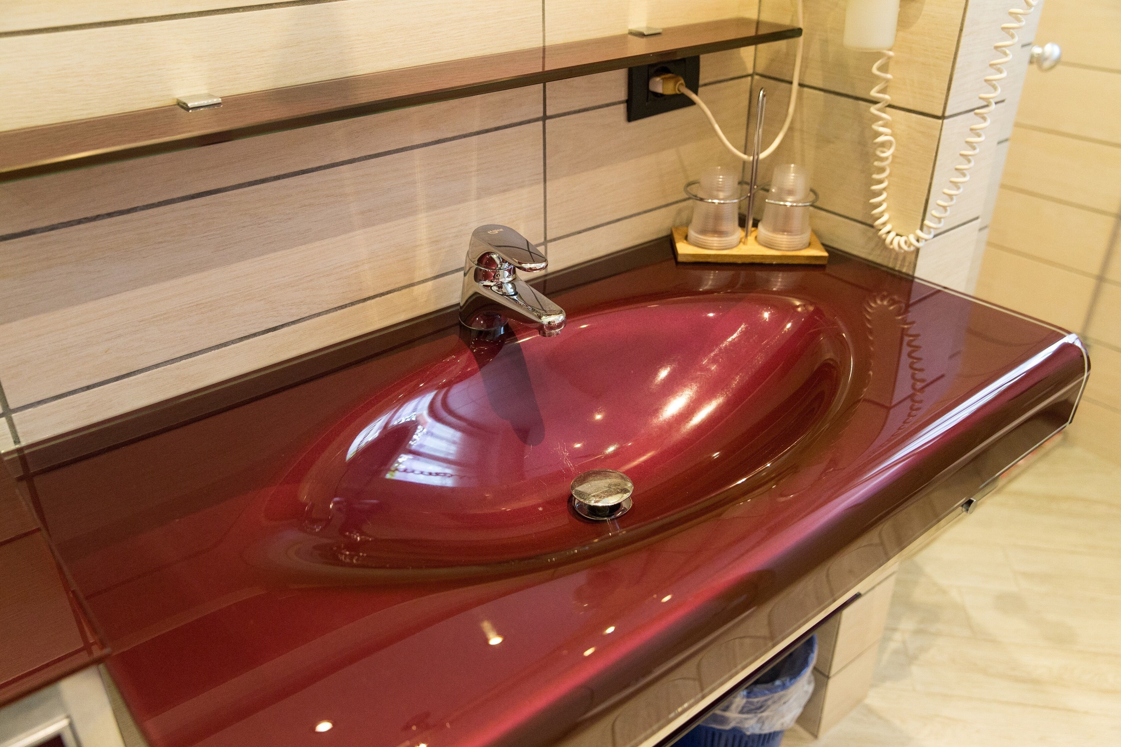 A bathroom with a red sink, a mirror, and a towel rack.