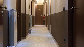 Un pasillo de hotel con suelo de diseño geométrico, puertas a ambos lados e iluminación empotrada.
