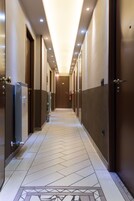 Un pasillo de hotel con suelo de diseño geométrico, puertas a ambos lados e iluminación empotrada.