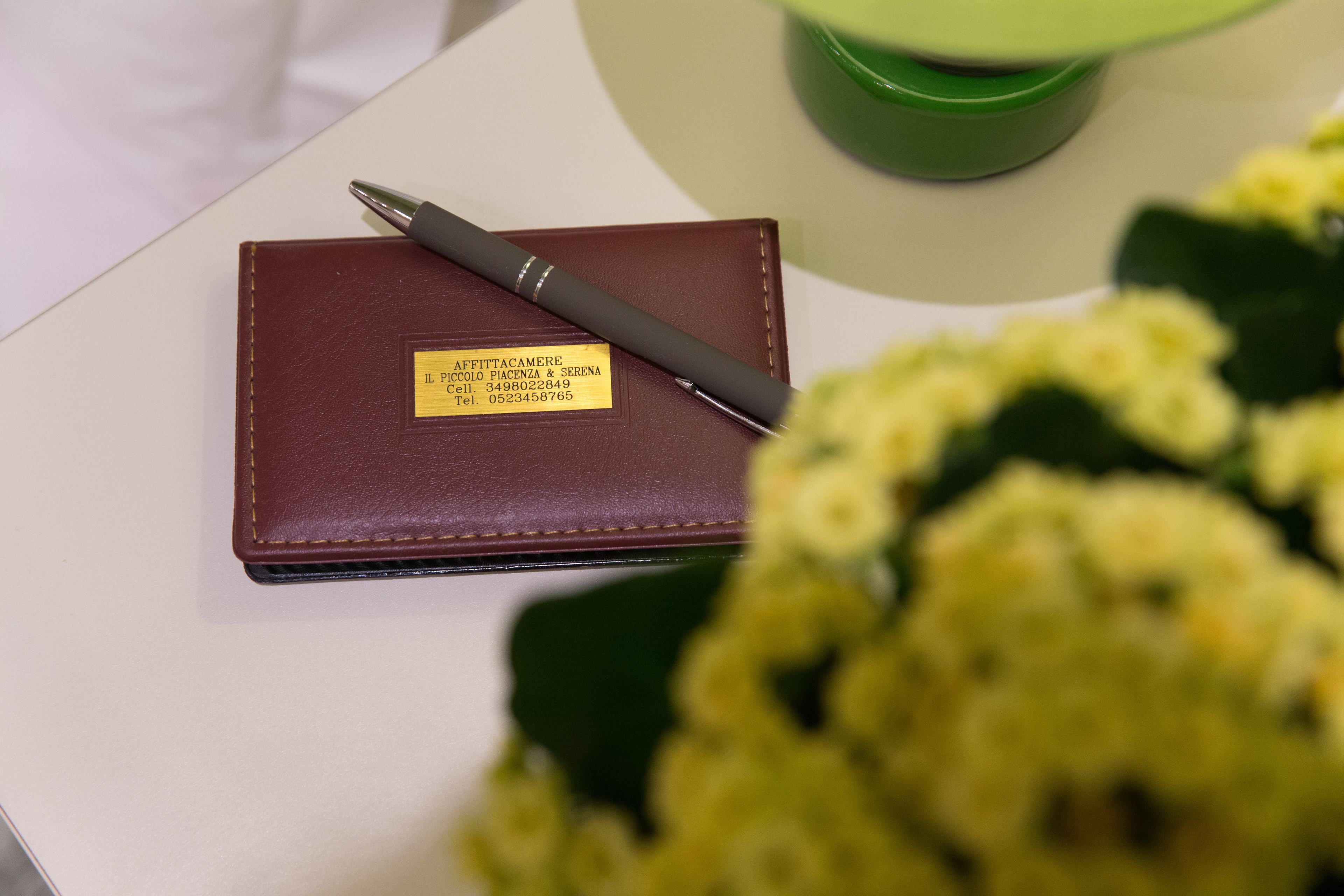 A brown leather wallet with a name tag and a pen on top.