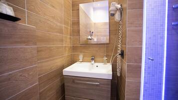 Ein modernes Badezimmer mit einem weißen Waschbecken, Holzwandverkleidung, einem Spiegel und einer Duschkabine.