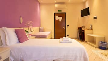 A hotel room with a bed, a desk, a chair, a TV, and a bathroom.