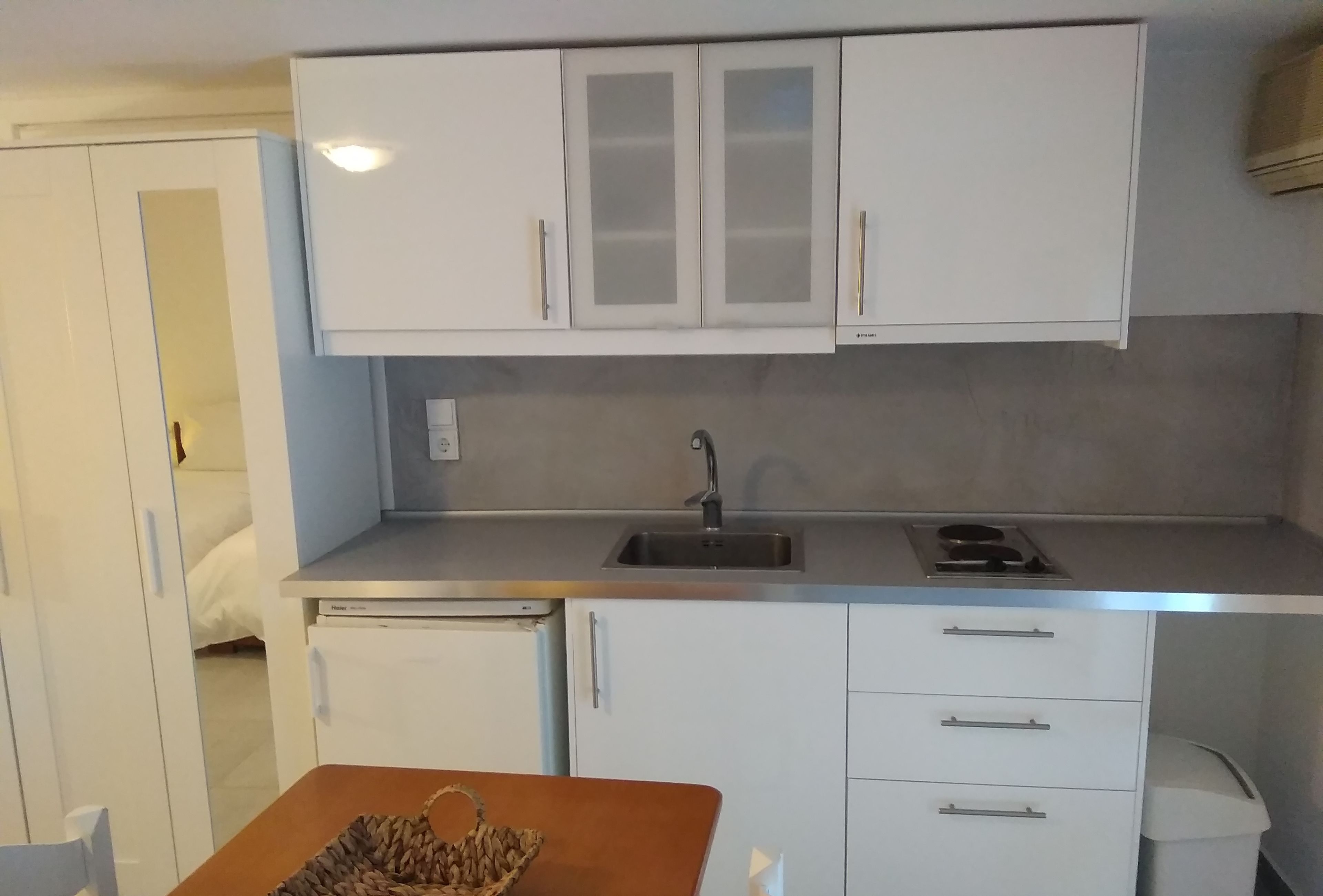 A compact kitchen with white cabinets, a stainless steel sink, and a small countertop.