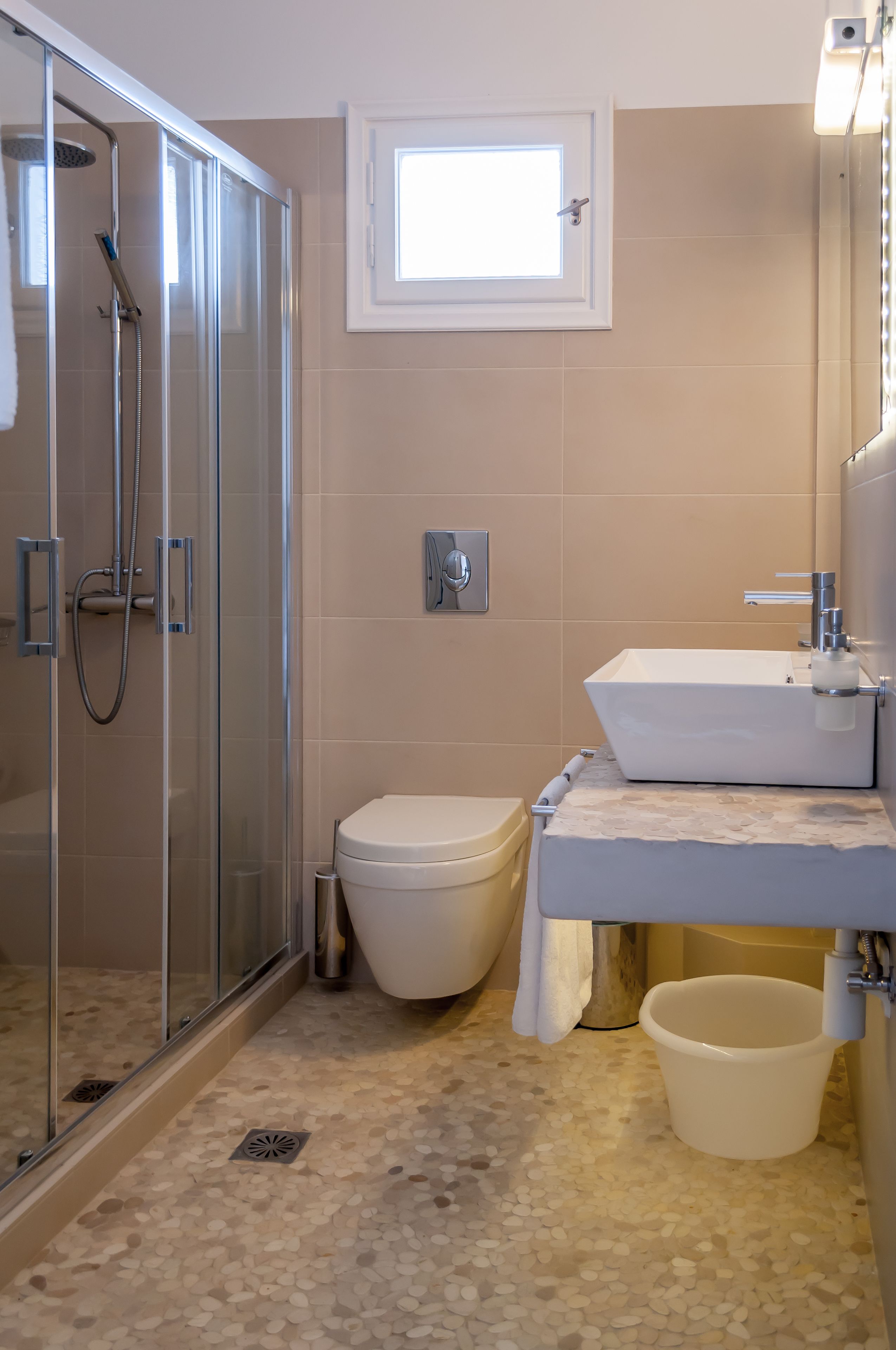 A modern bathroom with a glass-enclosed shower, a toilet, and a sink with a mirror.