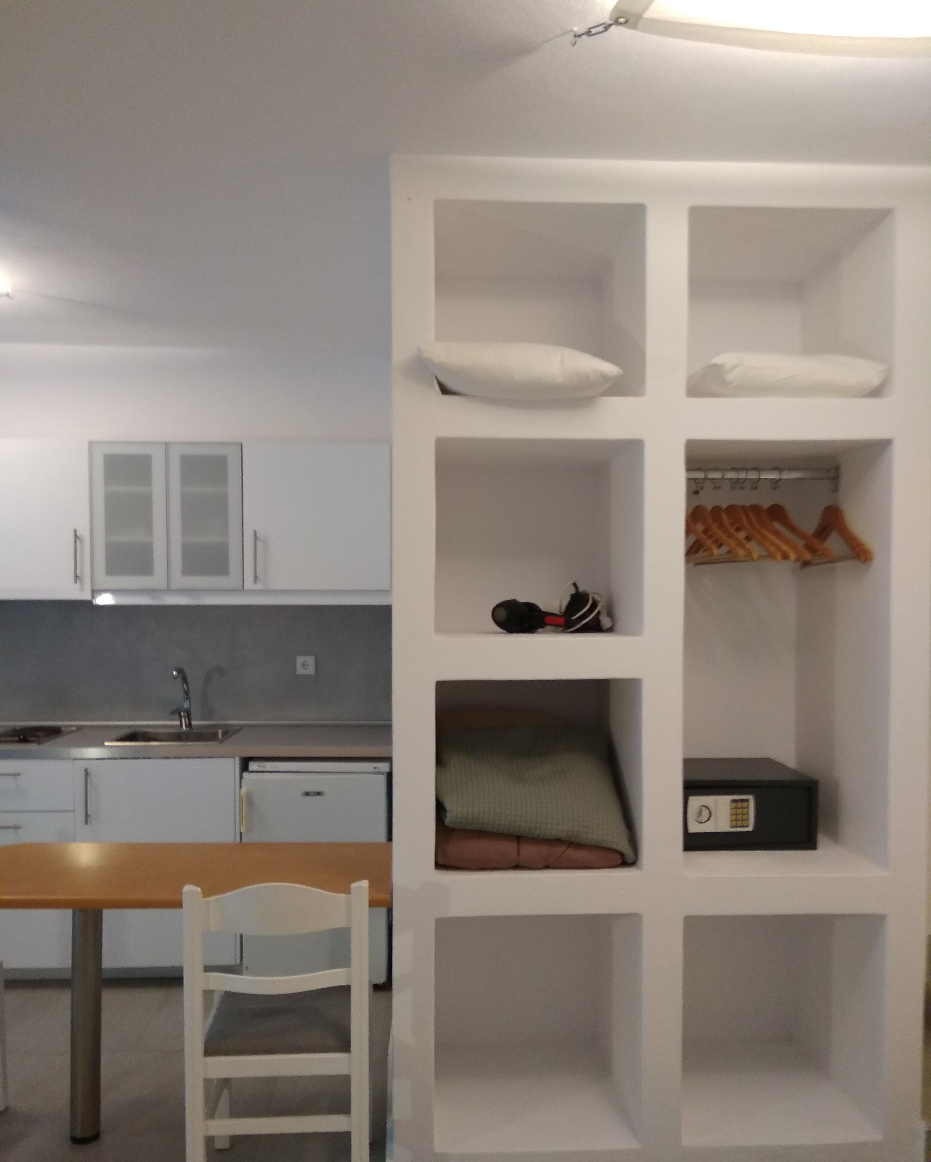 A compact kitchen with white cabinets, a sink, and a dining area with a table and chair.