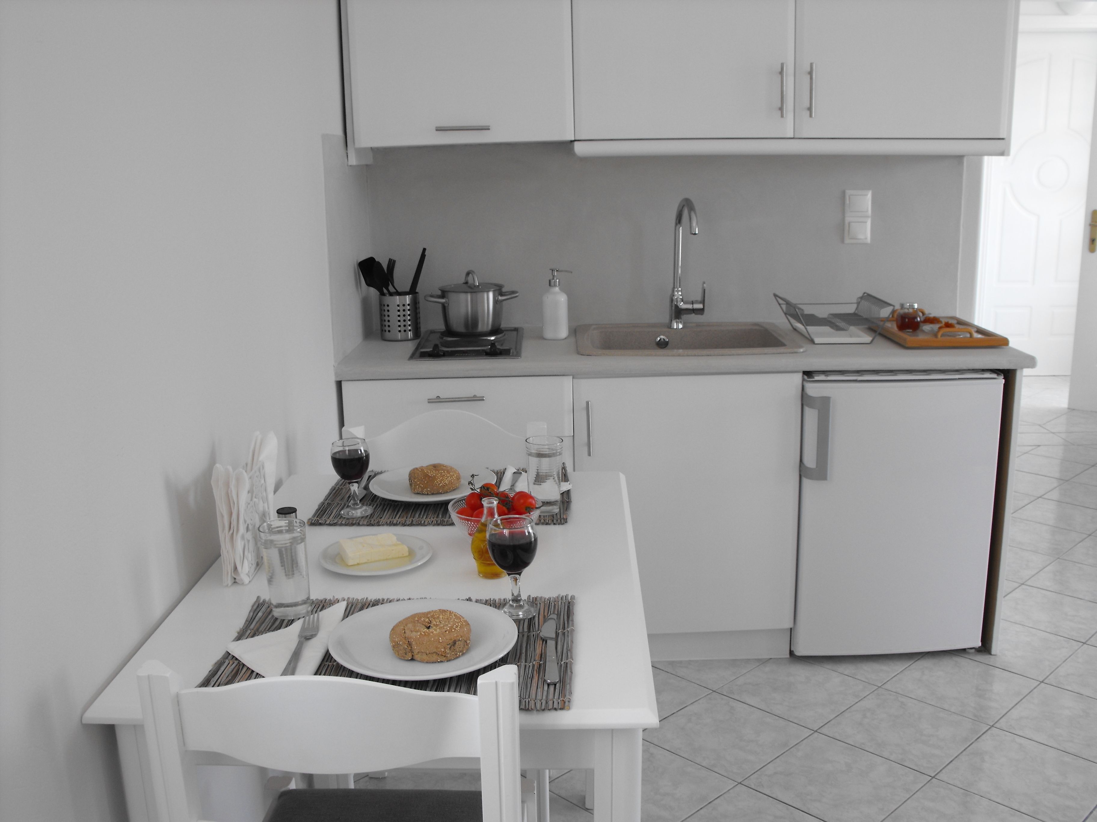 A modern kitchen with white cabinets, a sink, and a dining area with a table set for two.