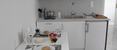 A modern kitchen with white cabinets, a sink, and a dining area with a table set for two.