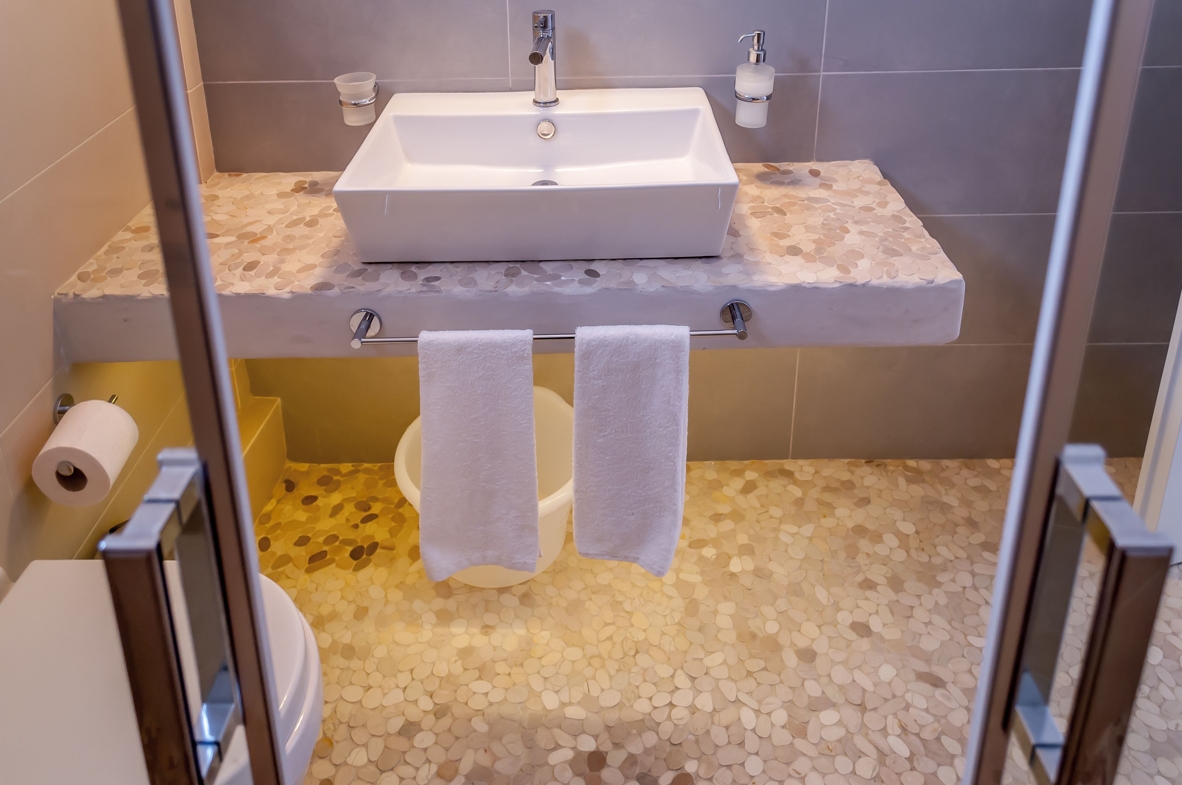 Et badeværelse med en hvid vask, toilet og bruseområde.