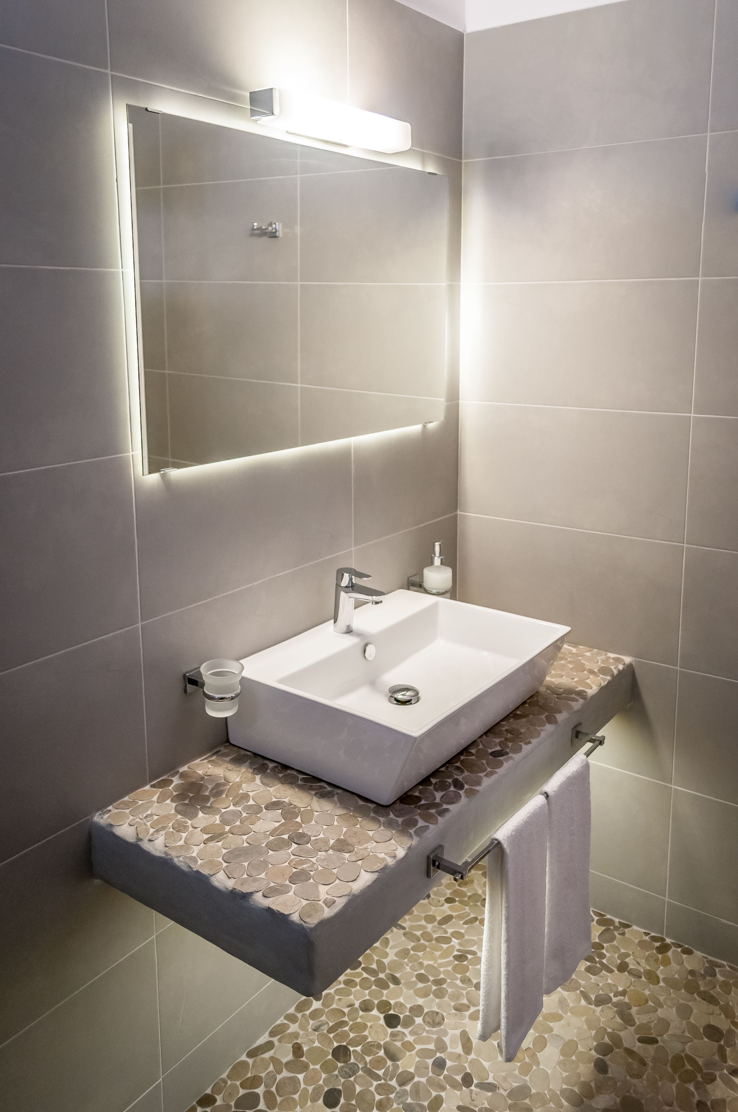 A modern bathroom with a rectangular sink, a mirror, and a towel rack.