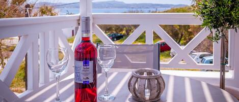 Una mesa con una botella de vino, dos copas y una vela en un balcón con vistas panorámicas.